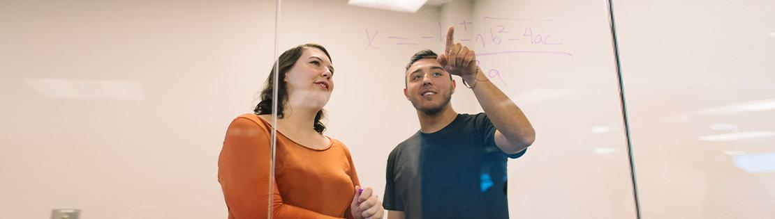 a student tutor assists a student with a math equation in a Pima study room